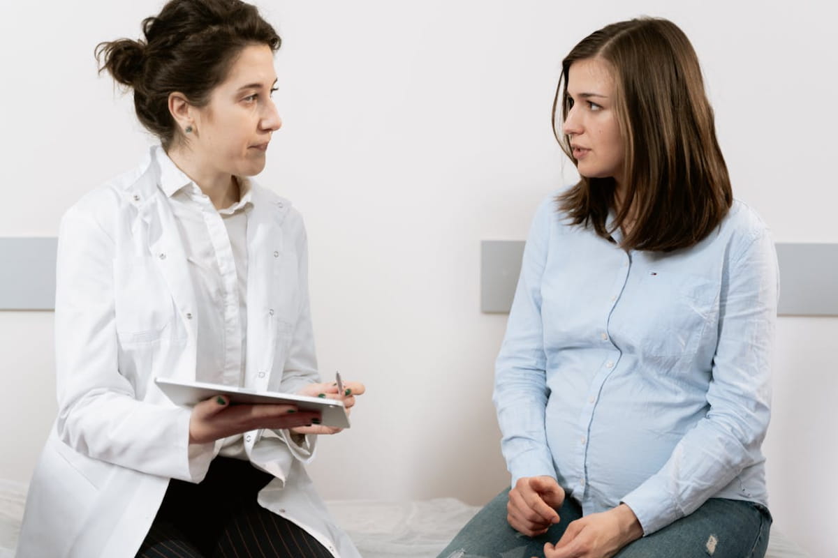 A doctor listening to a pregnant woman during a pelvic health appointment
